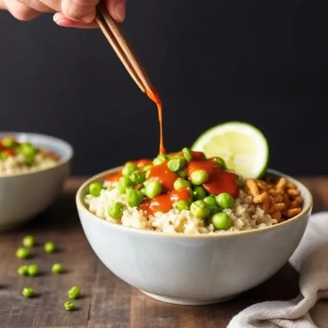 Edamame and brown rice bowl drizzled with Sriracha sauce, a spicy, protein-packed plant-based meal with 19g of protein