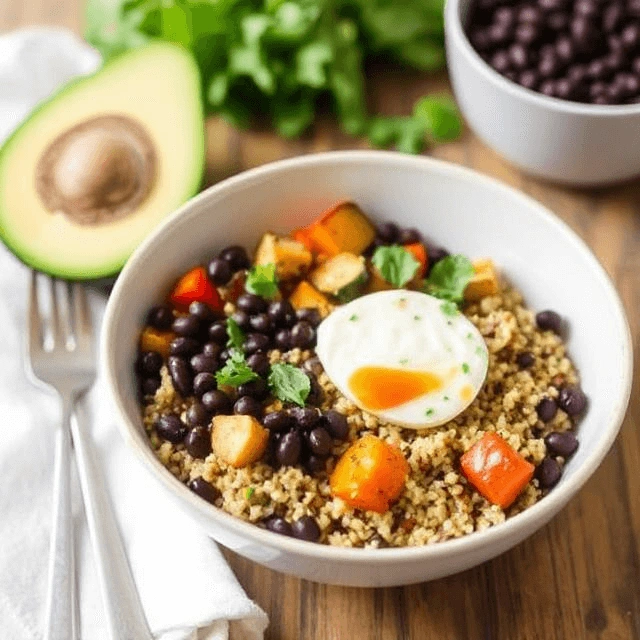 Colorful quinoa bowl with roasted vegetables and black beans, garnished with avocado slices