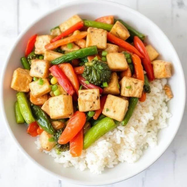 A colorful Tofu & Veggie Stir-Fry with crispy tofu cubes, bell peppers, broccoli, and carrots, all tossed in a savory stir-fry sauce.