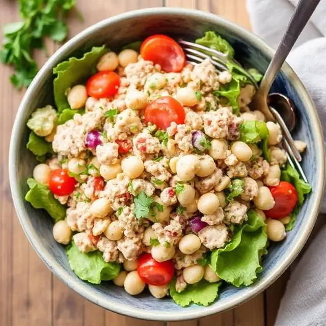 Fresh tuna and white bean salad with cherry tomatoes, red onion, and parsley in a rustic bowl.