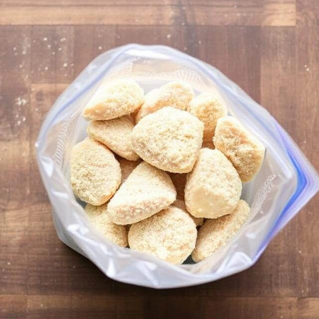 Pieces of chicken being added to a zip-top bag filled with the coating mixture, ready to be shaken.