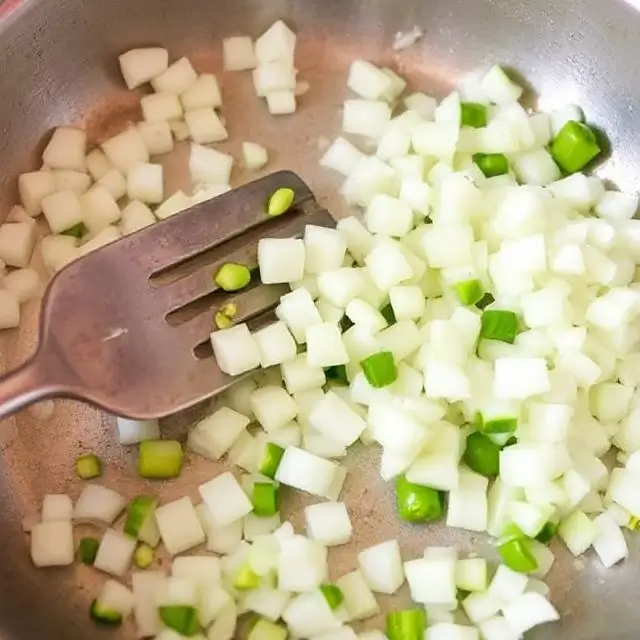 Diced onions sautéing in a skillet with olive oil on medium heat