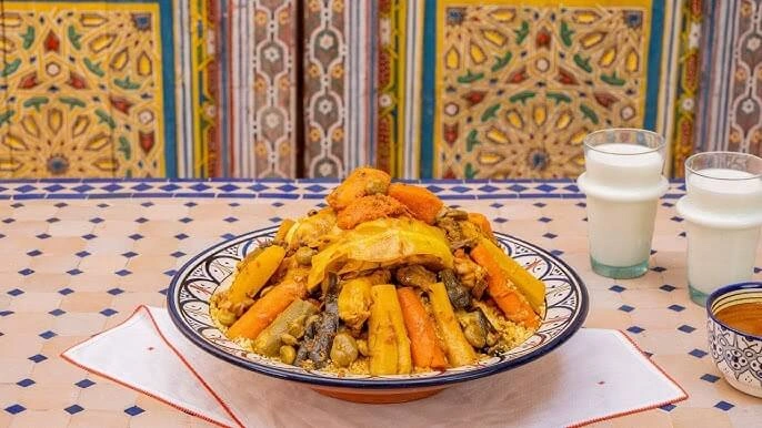 A plate of fluffy couscous served with vegetables and herbs, garnished with a light drizzle of olive oil.