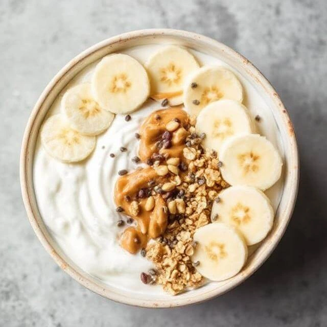 A creamy Greek yogurt bowl topped with a swirl of peanut butter, fresh fruit, and a sprinkle of nuts.